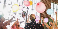 A vibrant celebration scene featuring diverse friends, including women and men of various ethnicities, joyfully tossing colorful balloons in the air, creating a festive atmosphere.