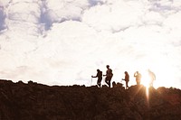 Silhouetted hikers on a rocky mountain ridge at sunrise. Group of hikers with walking sticks. Outdoor adventure, hiking, and mountain exploration. Hiking adventure on mountain trail.