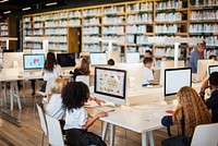 Students in library using computers. Diverse group of children learning. Library setting with computers. Kids engaged in educational activities. Young students learning on computers in school library