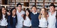 Group of diverse students in a library. Students in uniforms, library setting. Happy students, diverse group, library environment. Young diverse students learning together in library.