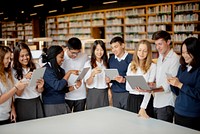 Diverse group of students in a library using tablets. Students engaged with technology. Diverse students learning with tablets in library. Diverse young men and women students using tablet in library