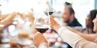 Group of people raising wine glasses in a toast. Diverse hands holding wine glasses. Celebration with wine, friends, and toasting. Cheers with wine glasses. Diverse people tasting and celebrating.