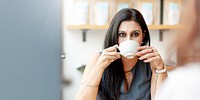 Business Woman drinking coffee at a cafe. Middle aged woman enjoys coffee. woman drinking coffee while meeting. The woman is seated, enjoying her coffee in a relaxed setting.