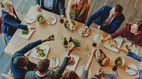 A diverse group of men and women celebrating at a dining table. The joyful gathering features toasts with drinks, delicious food, and a warm atmosphere, showcasing unity and friendship.