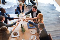 Group of diverse people enjoying meal together, toasting with wine glasses around a dining table, celebrating friendship and connection in a lively atmosphere. Diverse people celebrating and toasting.