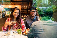 A couple enjoying coffee at a cafe. Smiling and relaxed, they share a moment. The cafe setting is cozy, with warm lighting and a friendly atmosphere. Young Indian friends eating lunch at restaurant.