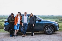 Group of diverse friends on road trip, standing by car. Diverse group of friends enjoying travel. Road trip vibes with friends, car, and nature. Happy travelers on an adventure. Friends on a trip