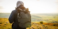 Person with backpack in outdoor setting, wearing a hoodie. Backpack and hoodie in focus. Outdoor adventure with backpack and hoodie. Scenic view in background. Man hiking in British nature.