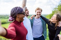 Group of diverse friends laughing outdoors, enjoying nature. Friends bonding, smiling, and having fun in a green, open space. Happy, diverse group outdoors. Happy friends hiking in British nature.