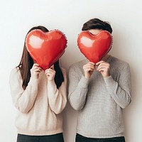 Young chubby couple balloons hiding heart.