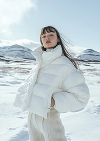 Young woman is wearing minimal white winter jacket snow photography mountains.