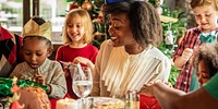 A joyful family gathering featuring a diverse group of children and adults celebrating Christmas. The festive Christmas atmosphere includes laughter, gifts, and holiday decorations.