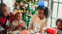 Family celebrating Christmas, exchanging gifts by a decorated tree. Smiling, joyful moments with festive hats. Warm, cheerful holiday atmosphere. Black family celebrating Christmas.