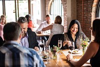 A diverse group of people enjoying a meal in a cozy restaurant. The scene features group of diverse friends sharing laughter and good food together.