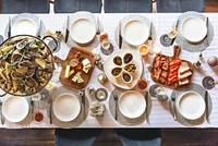 Elegant dining table set with seafood, cheese, and charcuterie. Plates and glasses arranged neatly. Seafood, cheese, and charcuterie create a gourmet feast. New Year's eve dinner party, top view.