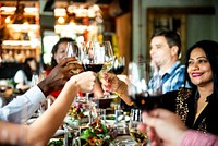 Group of diverse people toasting with wine glasses at a dinner celebration. Diverse group of people enjoying a festive Christmas dinner gathering, clinking glasses in a cheerful atmosphere.