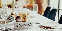 Elegant reserved table setting with wine glasses, plates, and festive decor. Reserved sign on table. Reserved for special occasions. Reserved for guests.