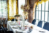 Elegant dining table set for a festive Christmas celebration with white tablecloth, candles, and decorations. Bright, festive, and inviting atmosphere for a Christmas celebration.