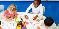 Children in a classroom, diverse group of kids learning together. Young students, in educational activities, sharing a table, focused on their work. Young diverse children learning in classroom.