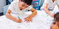 Children drawing at a table, focused on creativity. Kids in a classroom, engaged in art. Young students, art supplies, and creative expression. Young school children drawing in class.