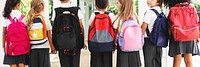 Children with backpacks, standing in a row. Diverse elementary students in school uniforms. Diverse group of kids elementary students back view. Elementary students with Backpacks and school uniforms.