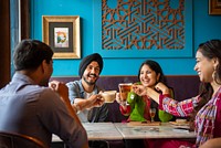 Group of South Asian friends enjoying drinks at a cafe. Smiling, chatting, and toasting. Happy moments, vibrant setting, diverse group, lively atmosphere. Happy Indian friends at cafe