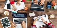 An Indian group of friends, collaborate at a wooden table, using laptops and smartphones for a productive brainstorming session. Indian group using devices and brainstorming together