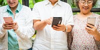 Three elderly people using smartphones, smiling and engaged. Diverse group enjoying technology, connecting and sharing moments on their phones. Diverse senior people using social media.