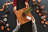 Hands exchanging a rustic gift box with pinecones, surrounded by autumn decor. Cozy, festive, and warm holiday atmosphere with pinecones and gifts. Friends exchanging a holiday gift.