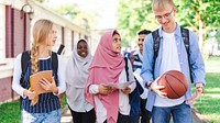 Diverse group of students walking outdoors, carrying books and a basketball. They are smiling and engaged in conversation, enjoying a day on campus. International students and muslim girls at school.