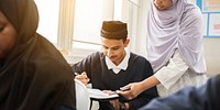 Muslim teacher in hijab assists students in classroom. Diverse classroom with attentive students. Education and learning environment with engaged students and teacher. Education and learning.