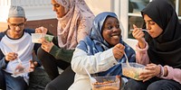 Group of diverse muslim friends enjoying lunch, sharing food and laughter. Young adults in casual attire, bonding over lunch in a relaxed setting. Muslim teenage students having lunch at school.