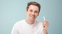 Smiling man holding a dental floss pick against a blue background. Dental care, flossing, and oral hygiene are key. Happy man, dental floss, and hygiene focus. Man with dental floss pick, hygiene.