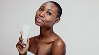 African woman holding skincare product, smiling. Skincare focus, beauty routine. African descent, glowing skin. Skincare, beauty, routine, product. African woman, beauty and skincare routine concept.