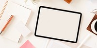 Top view of a workspace with a tablet, notebook, and coffee. Tablet and notebook on a desk. Tablet, notebook, and coffee create a cozy workspace. Blank tablet on aesthetic workspace desk.