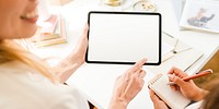 Two people collaborating, using a tablet and notebook. Bright workspace and technology. Hands writing, hands holding tablet, creative teamwork. Fashion designers working together with tablet.