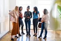 A diverse group of women in a bright office, discussing work. Diverse women standing together, smiling, and using a tablet. Professional and collaborative diverse group of women.