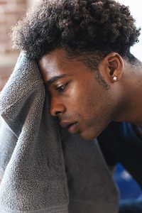 Black African American man with short curly hair using a towel. Close-up of a person with a towel. Relaxed expression, towel in hand, casual setting. African American man after exercise, tired face.