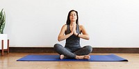 Woman practicing yoga on a mat, meditating in a serene pose. Yoga mat, meditation, and relaxation are key. Peaceful yoga session with a focus on calm and balance. Workout exercise concept photography.