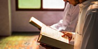 Two muslim people reading books in a sunlit room. Focus on hands holding books. Peaceful reading scene with natural light. Books and reading emphasized.