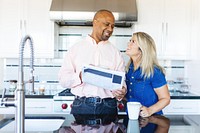 A couple in a modern kitchen, smiling and enjoying coffee. The man holds a tablet. Bright kitchen, happy couple, coffee time, modern kitchen setting. Couple are happy in modern kitchen.