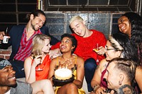 Group of diverse friends celebrating a birthday with cake and drinks, smiling and laughing together at a lively party. Joyful celebration with friends. Friends celebrating at birthday party.