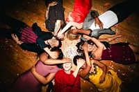 Diverse group of people lying on the floor, covering their eyes, surrounded by confetti. Celebration, joy, and diversity in a festive setting. Fun young diverse friends party night celebration.