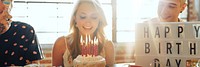 A woman celebrates her birthday with friends, smiling at a cake with candles. Birthday joy, birthday cake, and birthday celebration with friends. Fun birthday party with friends.