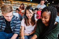 Diverse group of young adults studying in a library. Smiling students, books, and laptops. Engaged in learning, diverse group, library setting, teamwork. Diverse young people reading at library.