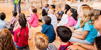 Children sitting on a classroom floor, attentively listening. Diverse group of kids, mixed genders, focused on a lesson. Classroom setting with engaged students. School children sitting on floor.