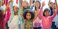 Group of diverse children with raised hands, smiling and excited. Kids in colorful clothes, joyful and happy. Multicultural group of children having fun. Cute little diverse kids, arms raised.