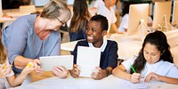 Teacher and students in a classroom with tablets. Diverse group learning with technology. Engaged students and supportive teacher using tablets for education. Exchange students learning in school.