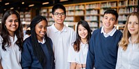 Group of diverse students in a library, wearing uniforms, smiling. Students in a library setting, diverse group, wearing uniforms, happy expressions. Diverse students in library, education concept.