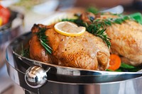 Roasted chicken with herbs and lemon garnish in a serving dish. Delicious roasted chicken, perfect for gatherings. Enjoy roasted chicken with fresh herbs. Sunday roast, roasted chicken with lemon.